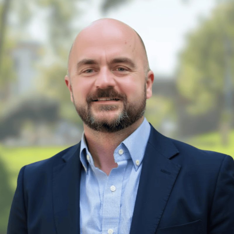 Chris Twiggs, President and Broker of Blair Allen Property Management, smiling outdoors in a navy blazer